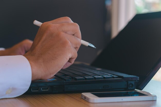 A close-up of a hand filling out a tax form with a pen, with a laptop showing IRS website in the background, emphasizing the importance of accurate documentation for tax benefits.