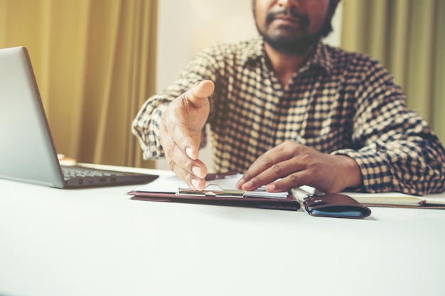 A person carefully filling out a tax form with a pen, with a laptop showing the IRS website in the background. The setting is a well-lit home office to reflect the meticulous nature of filing for tax benefits.