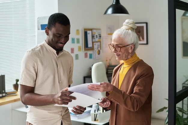 A friendly social worker assisting a family caregiver with filling out an application form. The setting should be a comfortable and supportive environment, with resources and information readily available.
